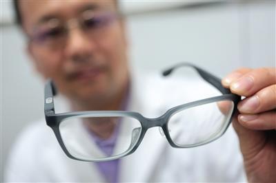 Doctor Song Hongxin displays a pair of 3D printed glasses at the Beijing Tongren Hospital in Beijing on July 30. [Photo: Beijing News]