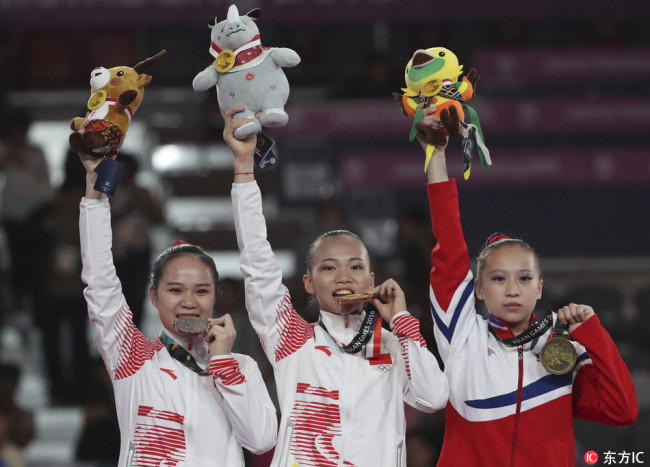 From left to right, silver medalist Luo Huan, gold medalist Chen Yile, both of China, and bronze medalist Kim Su Jong of North Korea celebrate after winning women's all-around gymnastics competition at the 18th Asian Games in Jakarta, Indonesia, Tuesday, Aug. 21, 2018.[Photo: Dita Alangkara/ IC]