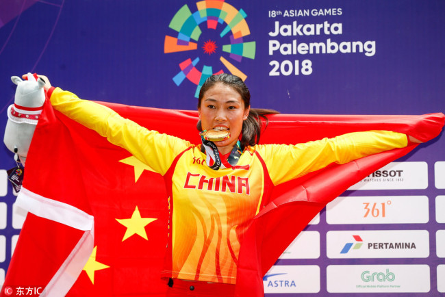 Zhang Yaru bites her gold medal during the awards ceremony of the women’s cycling BMX final at the 2018 Asian Games in Jakarta, Indonesia, August 25, 2018. [Photo: IC]