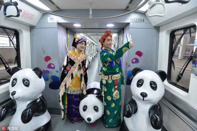 Two women take selfies(自拍) in a panda-themed subway train in Chengdu, Southwest China's Sichuan province, Sept 12, 2018. [Photo/IC]