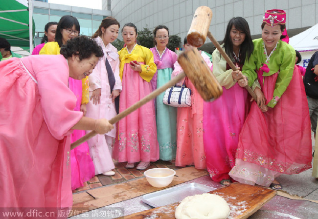 The picture taken on Sept 10, 2013, shows women in traditional costumes experience the making of songpyeon during the festival in Seoul. [Photo/IC]