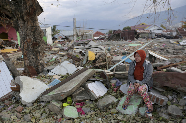 A villager sits on the ruins of her house destroyed by an earthquake and tsunami in Palu, Central Sulawesi, Indonesia, Saturday, Oct. 6, 2018. [Photo: AP/Tatan Syuflana]