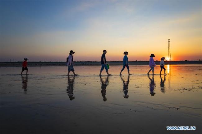 Tourists take a beachside walk(散步) in Haizhou Bay in Ganyu District of Lianyungang, east China's Jiangsu Province, Oct. 1, 2018. (Xinhua/Si Wei)