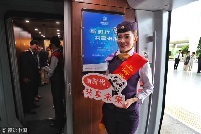 A train attendant stands in front of a poster for the import expo on a CIIE-themed train at Shanghai Hongqiao Railway Station on Wednesday, October 10, 2018. [Photo: VCG]