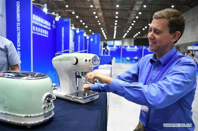 An exhibitor displays a coffeemaker during a pre-expo buyer and supplier matchmaking meeting of the 2018 China International Import Expo (CIIE) in Shanghai, east China, July 26, 2018.[Photo: Xinhua]