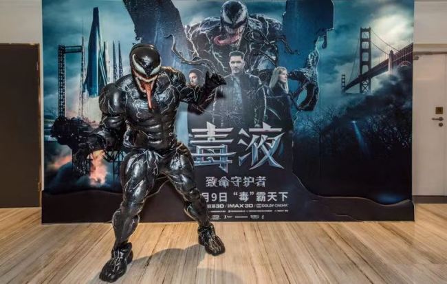 A mannequin dressed as Tom Hardy's character in the film Venom is positioned in front of the film poster at the premiere held in Beijing on Sunday, Nov 4, 2018. [Photo provided to China Plus]