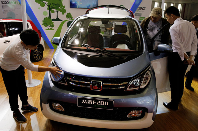 Visitors to the Beijing International Automotive Exhibition look at the Chinese automaker Zotye Auto's E200 electric vehicle displayed in Beijing, Tuesday, April 26, 2016. [Photo: AP/Andy Wong]