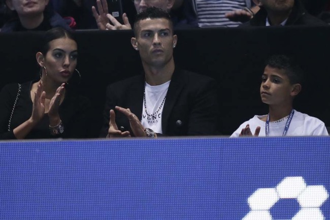 Cristiano Ronaldo, center, with his partner Georgina Rodriguez, and his son Cristiano Ronaldo Jr watches as Novak Djokovic of Serbia plays John Isner of the United States in their ATP World Tour Finals singles tennis match at the O2 Arena in London, Monday Nov. 12, 2018. [Photo: AP]