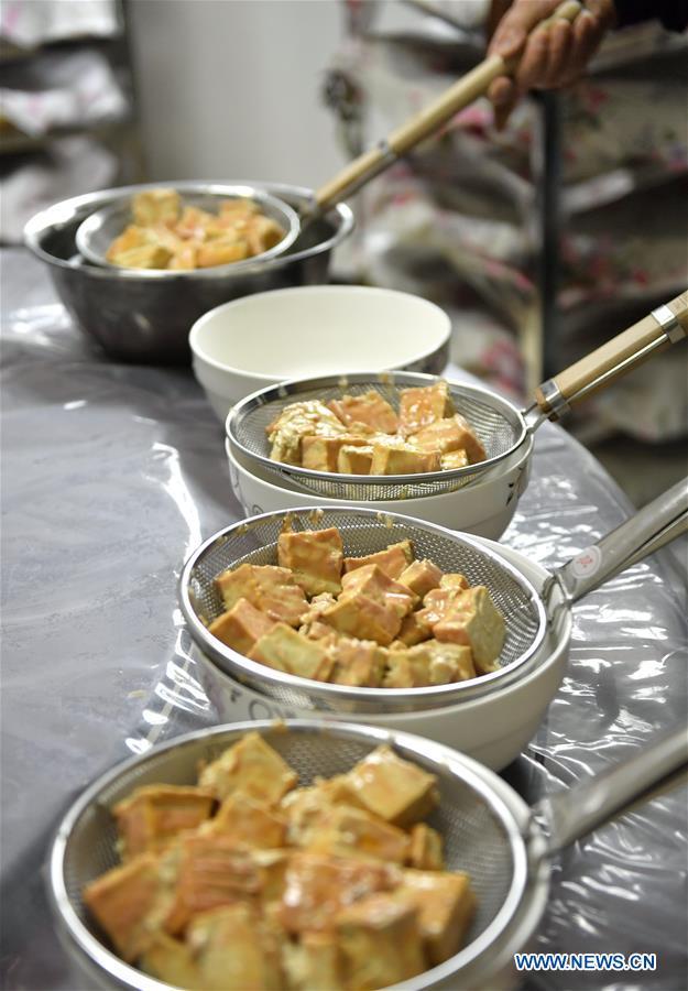 Local resident Yi Yinjie makes "mildewed tofu" by soaking(浸泡 jìnpào) them in alcohol(白酒 báijiǔ) in Zhushan Township of Xuan'en County in Enshi Tujia and Miao Autonomous Prefecture, central China's Hubei Province, Dec. 3, 2018.(Xinhua/Song Wen)