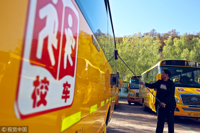 A bus driver cleans a school bus in Huachangyu village, Hebei Province, October 18 2018. [Photo: VCG]