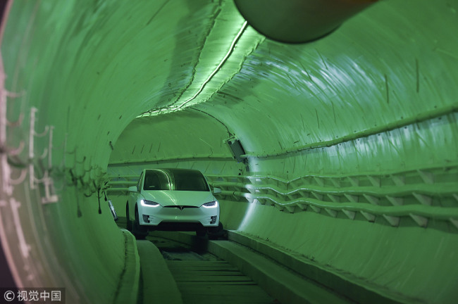 A modified Tesla Model X electric vehicle carrying Elon Musk, co-founder and chief executive officer of Tesla Inc., drives through the tunnel as it arrives for an unveiling event for the Boring Co. Hawthorne test tunnel in Hawthorne, California, U.S., on Tuesday, Dec. 18, 2018. [Photo: Pool via Bloomberg/Robyn Beck]