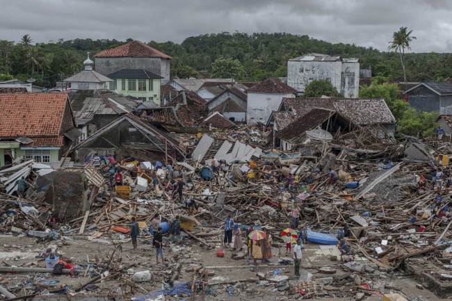 In this Monday, Dec. 24, 2018, photo, people inspect the damaged at a tsunami-ravaged village in Sumur, Indonesia. [Photo: AP] 