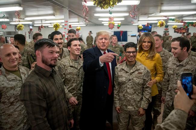 U.S. President Donald Trump and first lady Melania Trump pose for a photograph as they visit members of the military at a dining hall at Al Asad Air Base, Iraq, Wednesday, Dec. 26, 2018. [Photo: AP /Andrew Harnik]