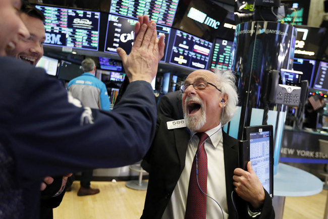 Traders Peter Tuchman, right, slaps a high five before the closing bell on the floor of the New York Stock Exchange, Wednesday, Dec. 26, 2018. The Dow closed up more than 1,000 points in best day for Wall Street in 10 years as stocks rally back from Christmas Eve beating.[Photo:AP]