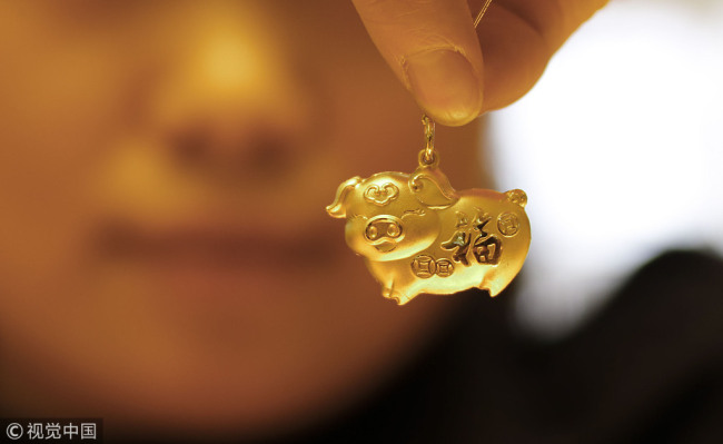 A gold pig-shaped locket(项坠 xiàng zhuì) carved(刻 kè) with the Chinese character "fu", which means good fortune, is pictured in Huaian(淮安), Jiangsu province, Dec 19, 2018. [Photo/VCG]