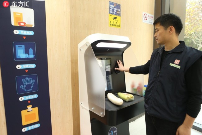 A customer scans his palm to pay for his purchases at an unmanned green grocery in Shanghai on December 1, 2018. [File photo: IC]