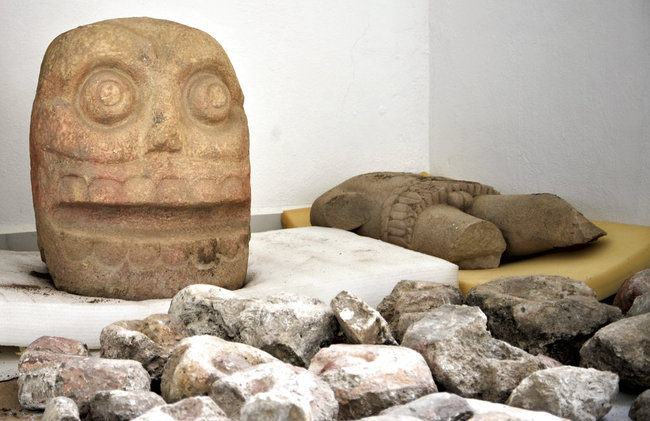 In this 2018 photo provided by Mexico's National Institute of Anthropology and History, INAH, a skull-like stone carving and a stone trunk depicting the Flayed Lord, a pre-Hispanic fertility god depicted as a skinned human corpse, are stored after being excavated from the Ndachjian–Tehuacan archaeological site in Tehuacan, Puebla state, where archaeologists have discovered the first temple dedicated to the deity. Although depictions of the god, Xipe Totec, had been found before in other cultures, a whole temple had never been discovered. [Photo: AP]