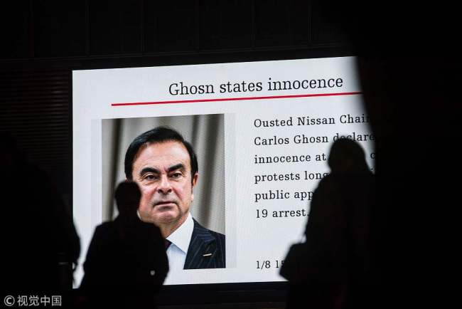 Pedestrians pass by a television screen showing a news program featuring former Nissan chief Carlos Ghosn in Tokyo on January 8, 2019. [File Photo: VCG]