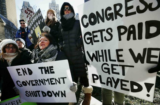 Government workers and their supporters hold signs during a protest in Boston, Friday, Jan.11, 2019. [Photo: AP]