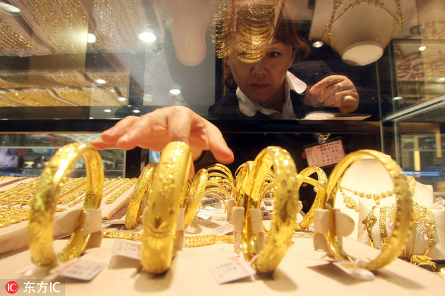 A Chinese saleswoman showcases gold bracelets at a gold and jewellery shop in Shanghai, China, 26 July 2011.[Photo: IC]