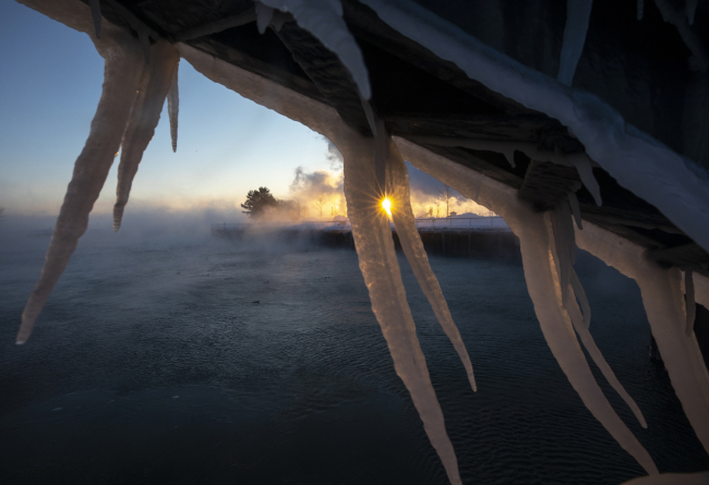 The sun rises behind icicles formed on the harbor in Port Washington, Wis., on Wednesday, Jan. 30, 2019. [Photo: AP/Jeffrey Phelps]