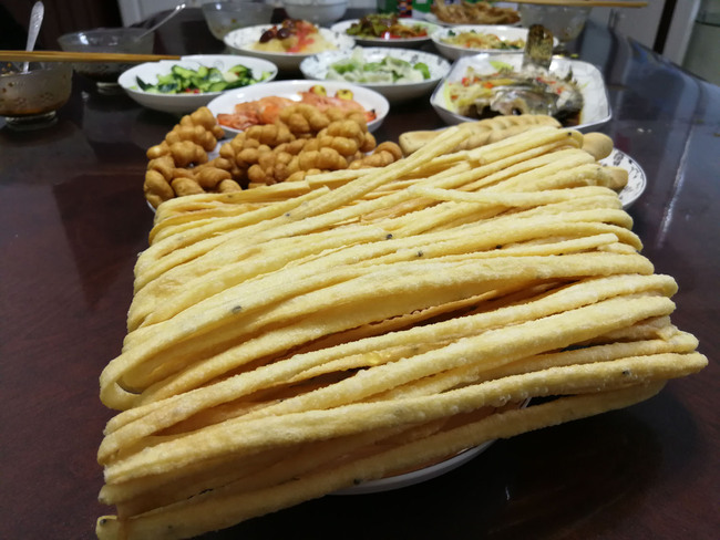 Sanzi, a fried dough twist, set out for a New Year's dinner in Lanzhou, Gansu Province, February 4, 2019. Fried dough twists are a traditional food in northwest China, where locals generally eat flour-based pastries ahead of the Lunar New Year. [Photo: China Plus/Sang Yarong]