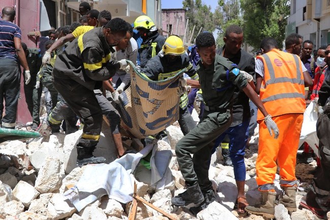 Emergency rescue staff carry the body of a victim over rubble at the scene of a car-bomb attack on February 4, 2019 in Somalia capital Mogadishu's Hamarwayne District. At least nine people were killed and several wounded when a car loaded with explosives blew up near a mall in a busy market in the Somali capital on Monday, police said. [Photo: AFP]