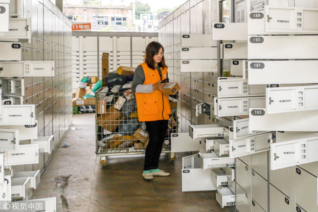 An employee puts parcels into self-service package lockers at a delivery service center at a university in Shanghai. [Photo: VCG]
