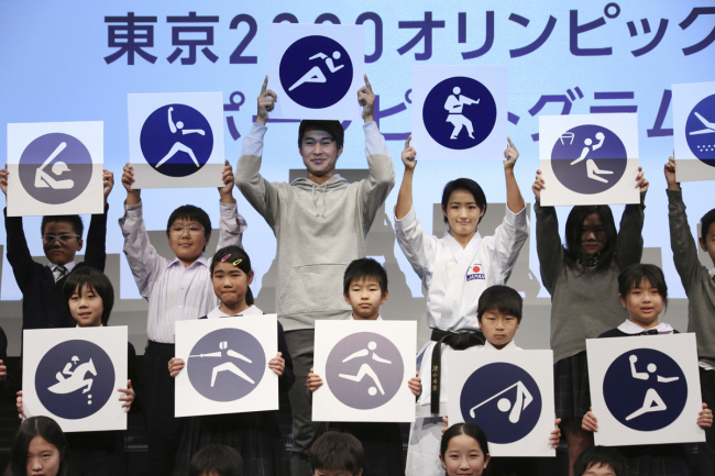 Rio Olympics athletics silver medallist Shota Iizuka, top center left, karate athlete Kiyo Shimizu, top center right, and elementary school students pose with pictograms of Tokyo 2020 Olympic sports events during a celebration to mark 500 days to go, in Tokyo, Tuesday, March 12, 2019. [Photo: AP]