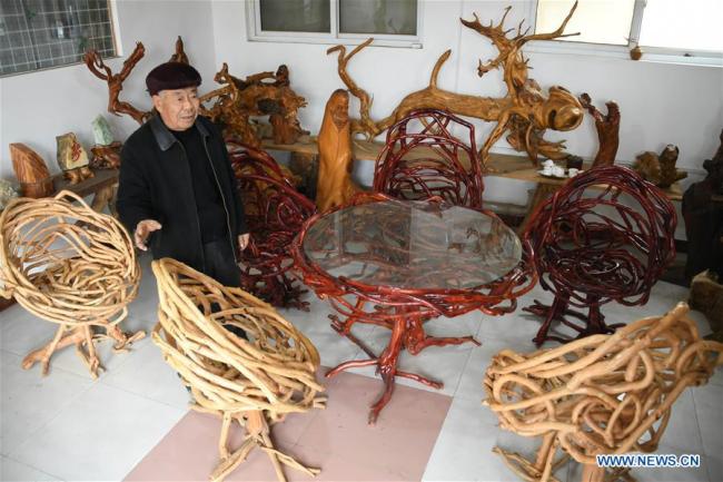 Zhang Weiren, owner of a 12-mu (0.8-hectare) peach orchard, shows some furniture made of peach trees at Langbu Village of Dianbu Town in Laixi City, east China's Shandong Province. [ Photo: Xinhua/Li Ziheng]