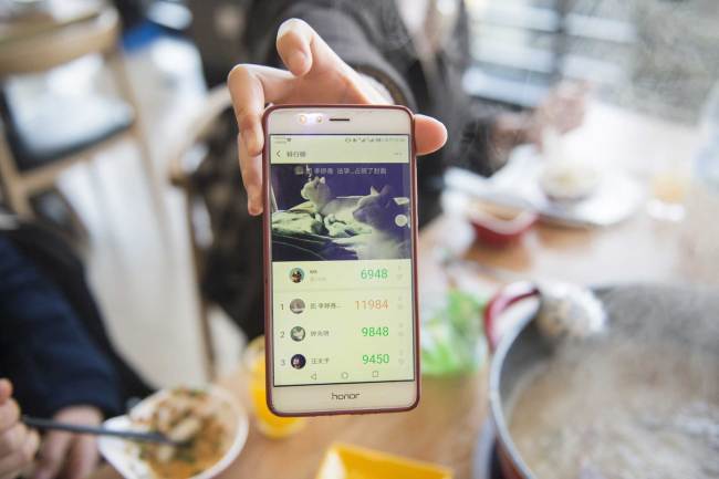 A student at Zhejiang Gongshang University presents(展示 zhǎnshì) the number of daily steps recorded in WeChat at an on-campus restaurant to get a discount on their bill on Wednesday, March 13, 2019. [Photo: IC]