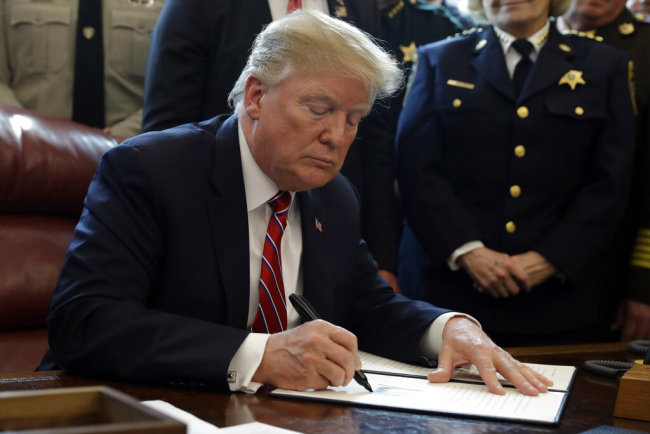 U.S. President Donald Trump signs the first veto of his presidency in the Oval Office of the White House, Friday, March 15, 2019, in Washington. Trump issued the first veto, overruling Congress to protect his emergency declaration for border wall funding. [Photo: AP/Evan Vucci]