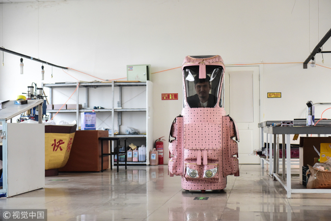 Zhang Renbing created a 1.6-meter car bag, which includes batteries(电池 diànchí), motors(发动机 fādòngjī) and wheels(车轮 chēlún) installed under the bag. [Photo: VCG]