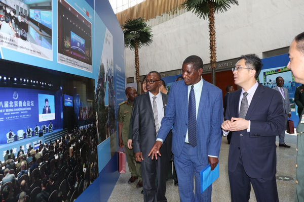 Acting director for AU Peace and Security, Admore Kambudzi (Center), takes a look at an exhibition board in an exhibition "Chinese People's Liberation Army: A Force for World Peace," which showcases the Chinese military's practices and achievements in safeguarding the world peace and advancing common development, in Addis Ababa, Ethiopia, on March 18, 2019. [Photo: China Plus]