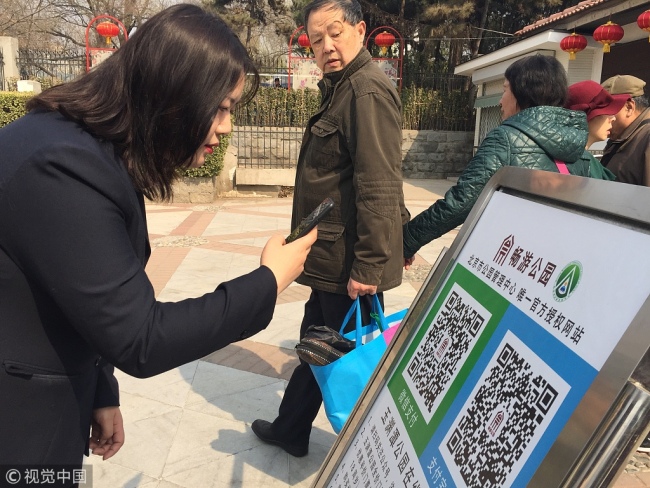 A visitor scans a QR code for an online purchase of a park ticket, Yuyuantan Park, Beijing, March 18, 2019. [Photo: VCG]
