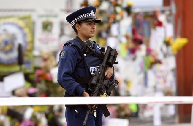 A policewoman patrols past a memorial wall outside the Linwood Mosque in Christchurch on March 21, 2019, six days after the twin mosque shooting massacre that claimed the lives of fifty people. [Photo: AFP]