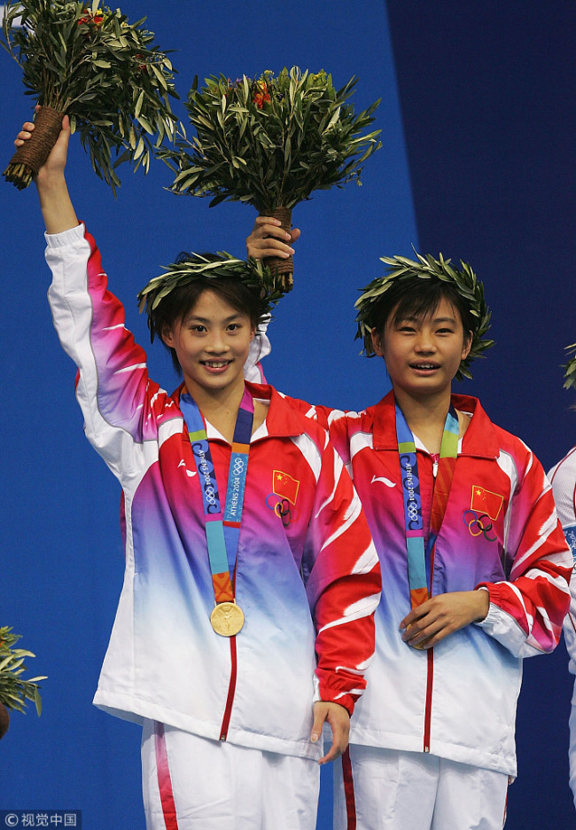 Li Ting (L) and Lao Lisha of China receive their gold medals for the women's synchronised diving 10 metre platform event on August 16, 2004 during the Athens 2004 Summer Olympic Games at the Aquatic Centre Indoor Pool at the Olympic Sports Complex in Athens, Greece. [File photo: VCG]