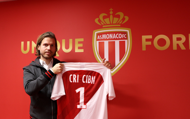 A man holding a club shirt with "CRI CIBN" prints. [Photo: China Plus]