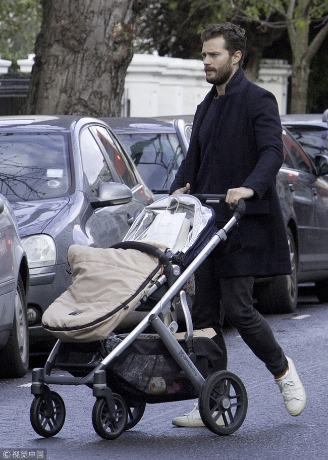 Jamie Dornan pushes a baby carriage, November 25, 2015, London, England. [File Photo: VCG]