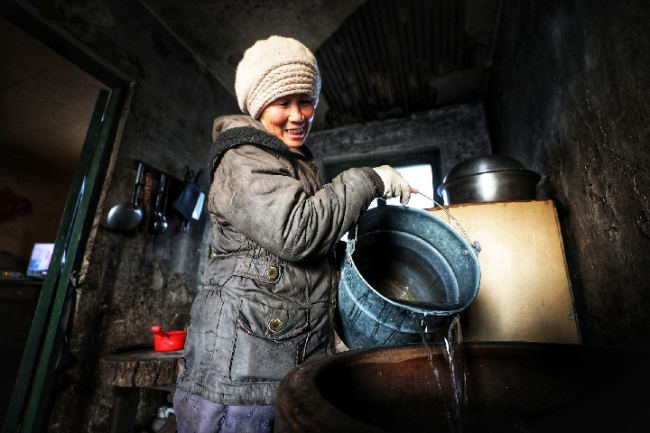 A villager collects water supplied by the train in the Changbai Mountains in Jilin Province. [Photo: Xinhua]