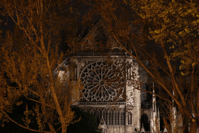 Firefighters (L) work to contain a fire near the north rose window at Notre-Dame Cathedral in Paris early on April 16, 2019. [Photo: AFP/Zakaria ABDELKAFI]  