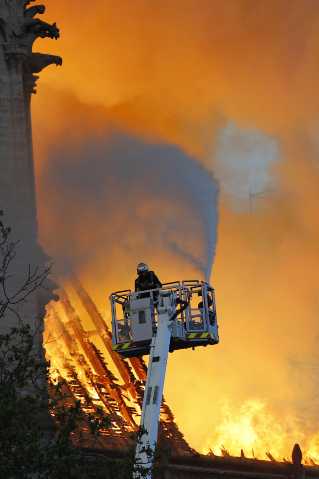 A fire fighter uses a hose as Notre Dame cathedral is burning in Paris, Monday, April 15, 2019. [Photo: AP]