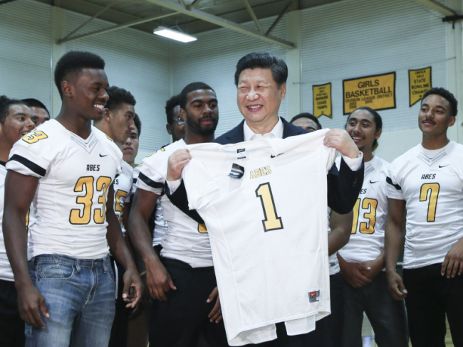 President Xi Jinping is presented with a football jersey by the school team during his visit to Lincoln High School, Tacoma, Washington State, September 23, 2015. [Photo: Xinhua]