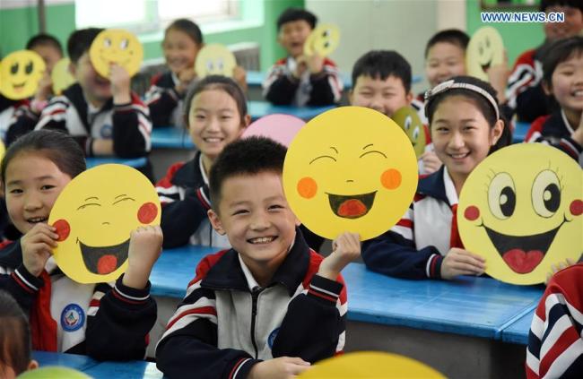 Pupils demonstrate smiley cards(卡片 kǎpiàn) to greet the upcoming World Smile Day at a primary school in Handan, north China's Hebei Province, May 7, 2019.[Photo: Xinhua]