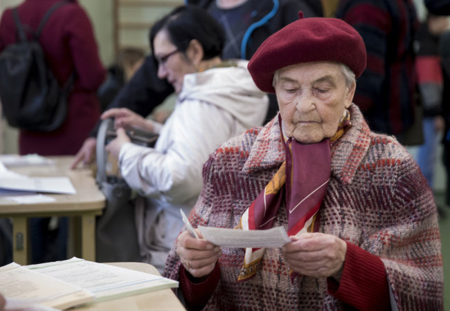 A Lithuanian woman reads a ballot paper at a polling station during the first round of voting in presidential elections in Vilnius, Lithuania, Sunday, May 12, 2019. [Photo: AP/Mindaugas Kulbis]