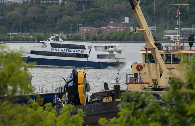 A helicopter is loaded, by crane, onto a barge after it crashed into the Hudson River on May 15, 2019 in New York. [Photo: AFP/Don Emmert]