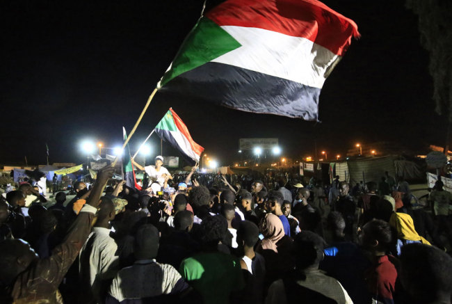 Sudanese protestors celebrate after an agreement was reached with the military council to form a three-year transition period for transferring power to a full civilian administration, in Khartoum, early on May 15, 2019. [File photo: AFP/Ashraf Shazly]