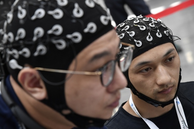 Competitors wearing headwears with sensors take part in a BCI (brain–computer interface) contest during the World Robot Conference (WRC) 2018 in Beijing, China, 15 August 2018. [File Photo: IC]