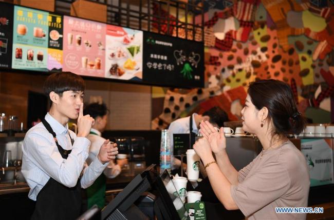 A staff member (L) communicates with a customer using sign language in a Starbucks coffee store in Guangzhou, south of China's Guangdong Province, May 19, 2019. [Photo: Xinhua]