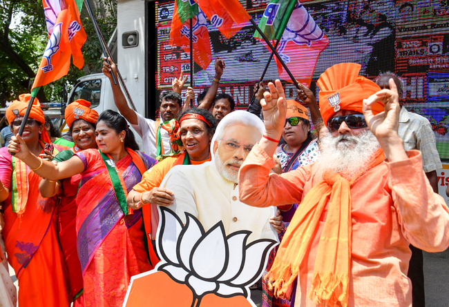 Indian supporters and party workers of Bharatiya Janata Party (BJP) dance and hold flags as they celebrate on the vote results day for India's general election in Bangalore on May 23, 2019. [Photo: AFP/MANJUNATH KIRAN]<br/>